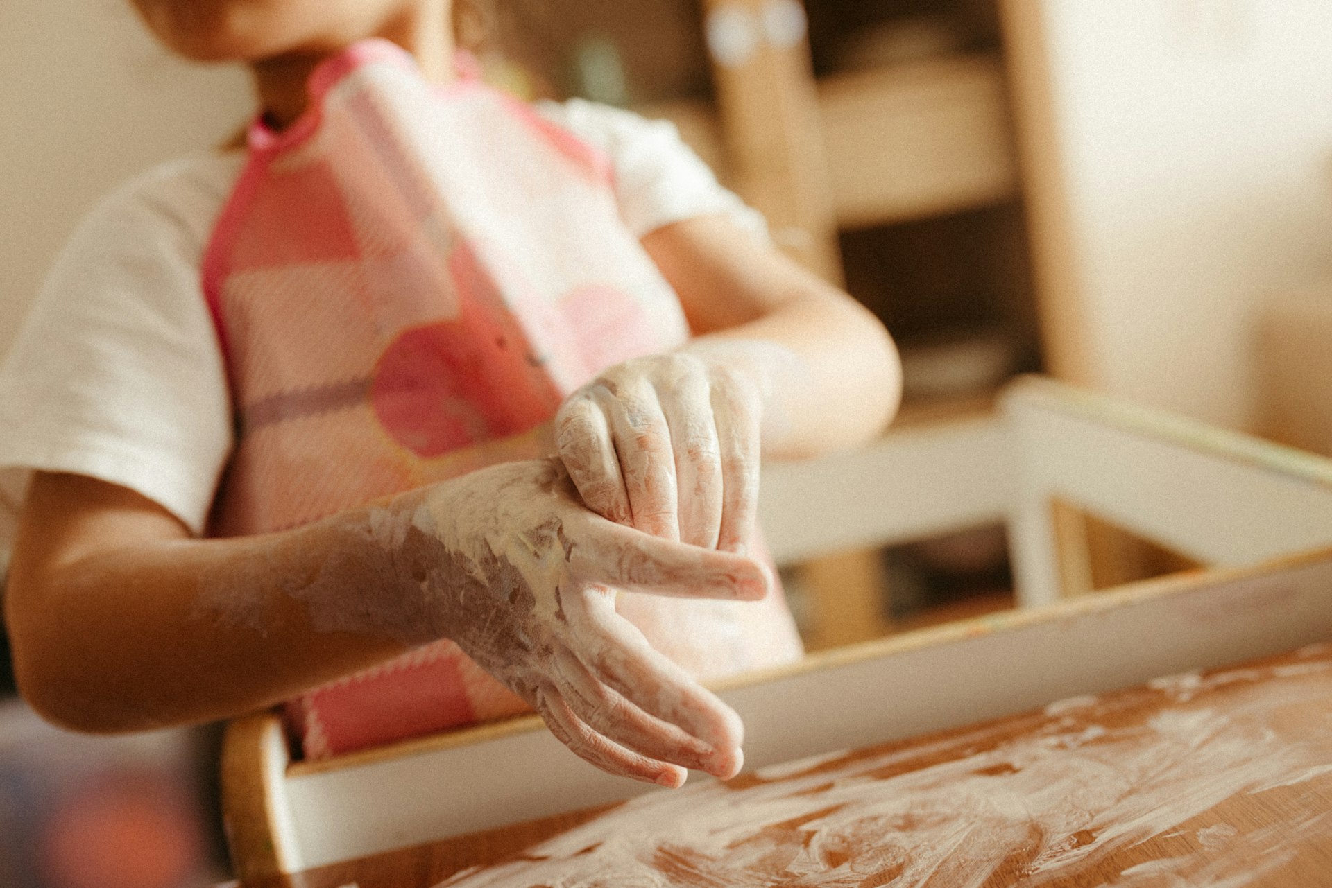 A child with flour on their hands and apron.